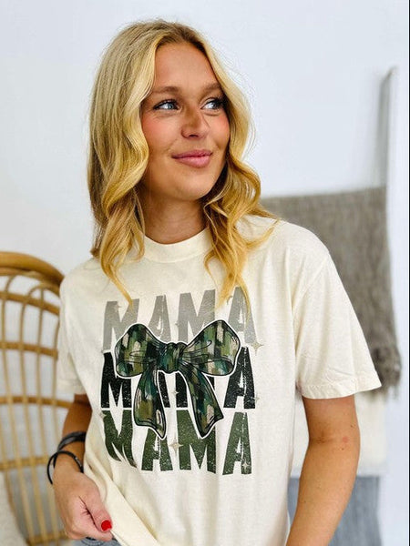Woman wearing a white t-shirt with 'MAMA' text and camouflage bow design.