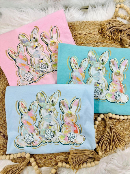 A collection of Easter-themed graphic tees with watercolor bunny designs, displayed on a neutral background.