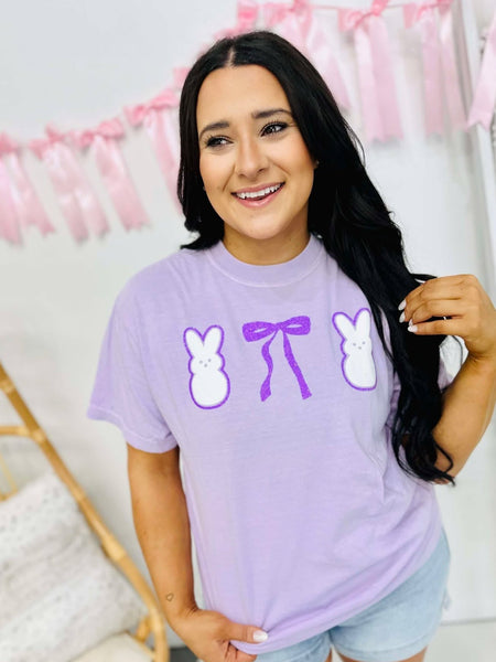 Woman wearing a purple t-shirt with graphic designs in a home setting