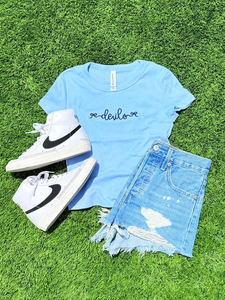 Light blue t-shirt with 'devils' text, white high-top sneakers, and denim shorts on grass