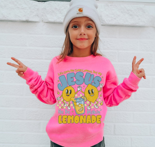 Child wearing a pink sweatshirt with colorful graphics and text, standing against a white background.